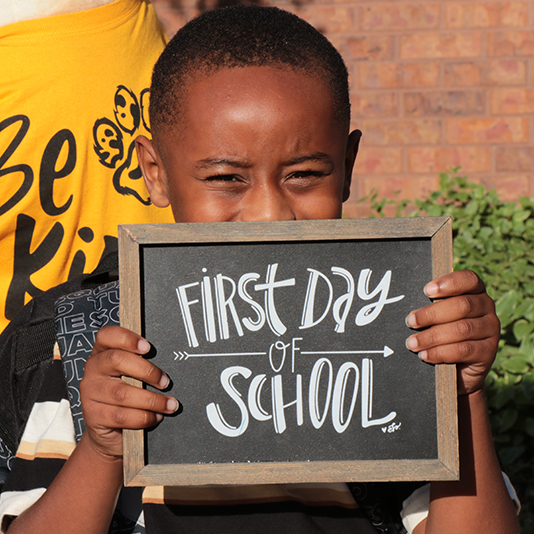  A student holds a sign saying first day of school